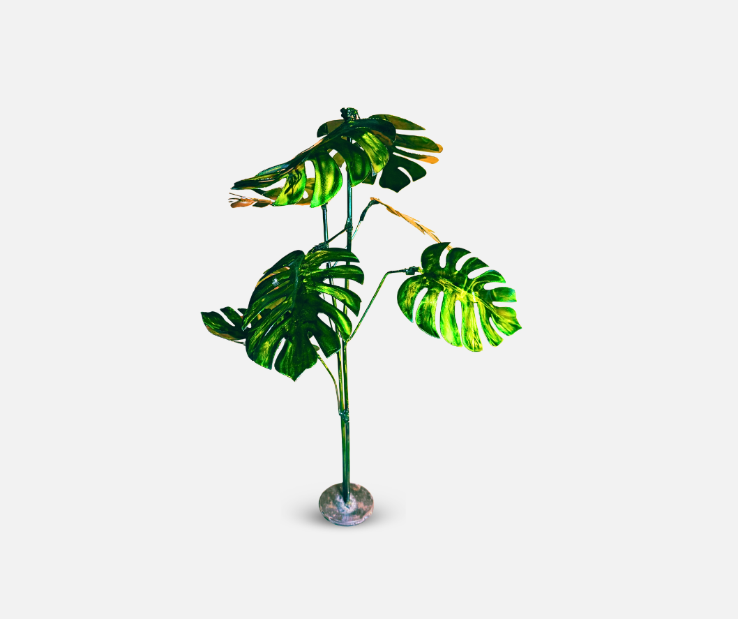 metallic green plant with leaves, stem and round base. metal sculpture designed to look like monstera plant.