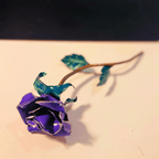 Purple rose with green leaves on a light surface