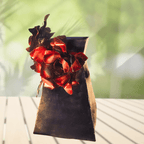 Decorative metal red flower arrangement on a black vase with a blurred green background