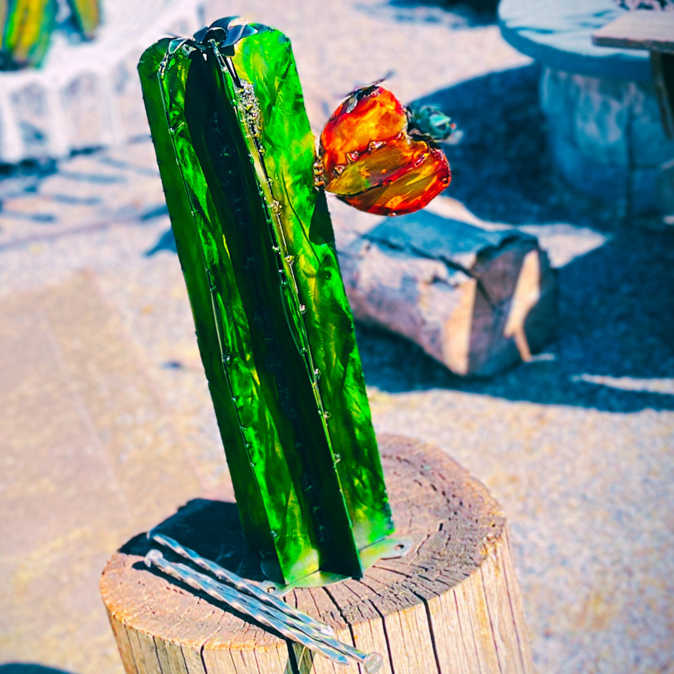 Green metal cactus on a stump with blurred landscape background