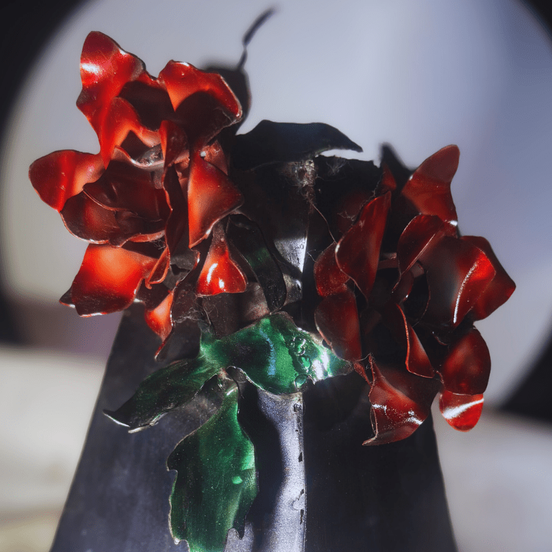 Close-up of a red and green metal plant under a magnifying glass