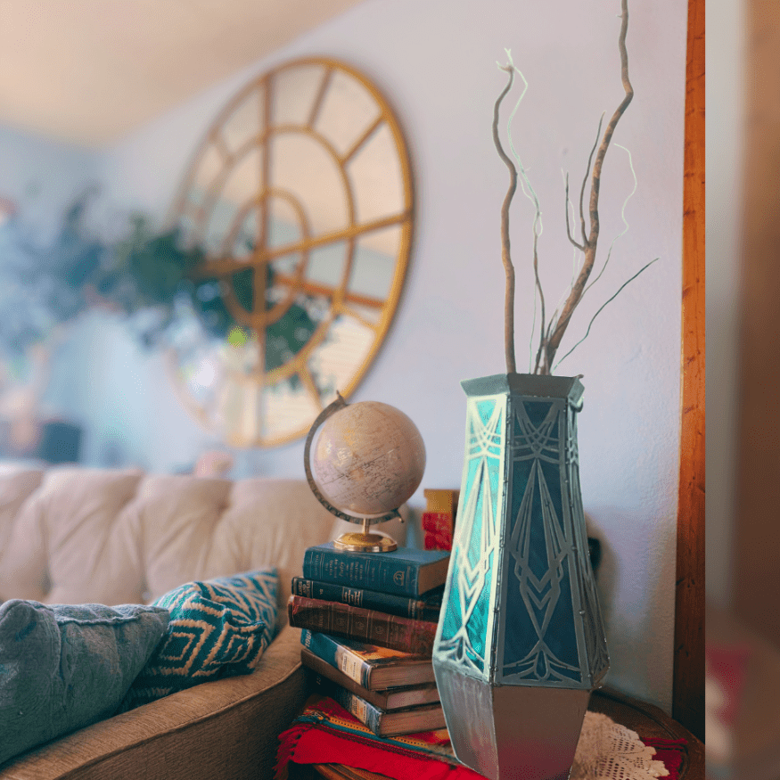 Decorative vase with branches on a stack of books in a living room setting.