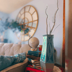 Decorative vase with branches on a stack of books in a living room setting.