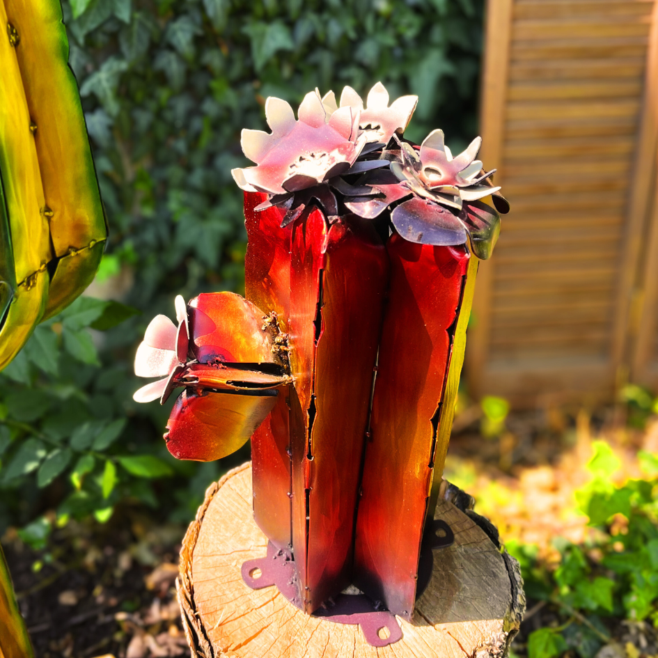 Metallic cactus flower sculpture on a wooden stump with a garden background
