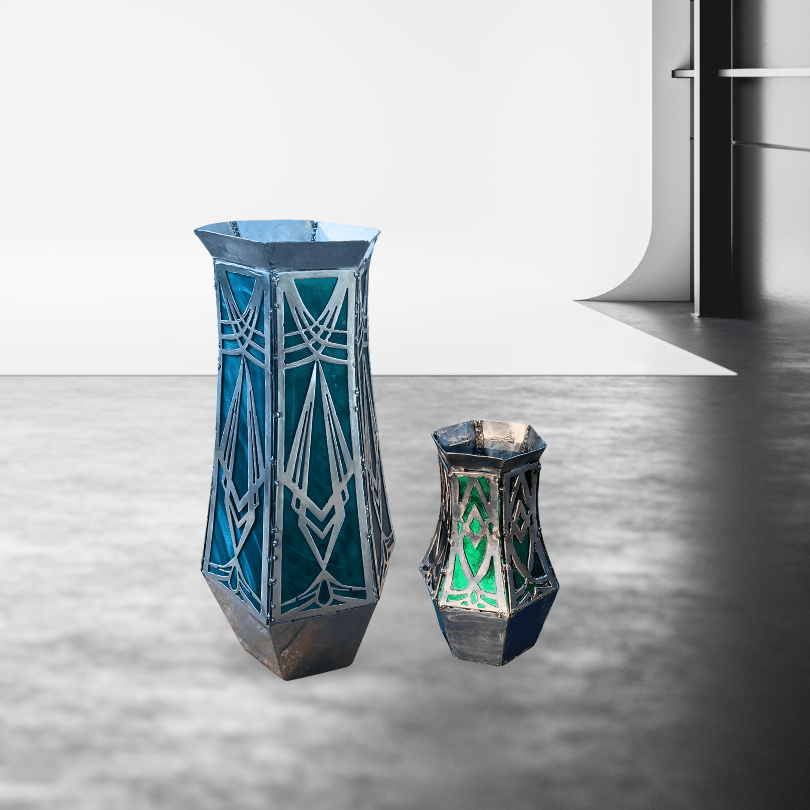 Two geometric metal vases on a reflective surface with a neutral background