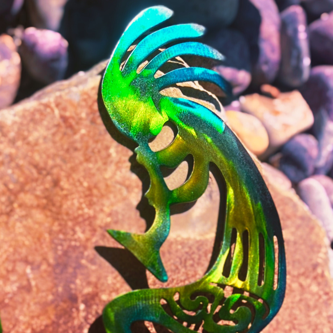 Metallic green and blue kokopelli metal art on a natural flagstone textured surface