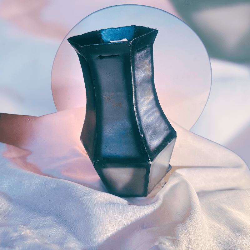 Black metal vase with geometric shape on a white fabric background