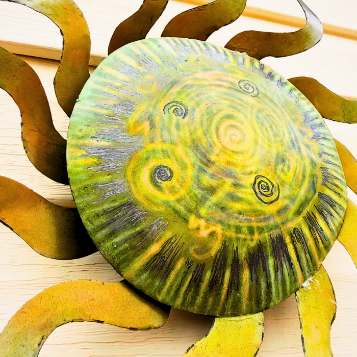 Artistic depiction of a sun with a spiral pattern on its center, surrounded by orange rays.