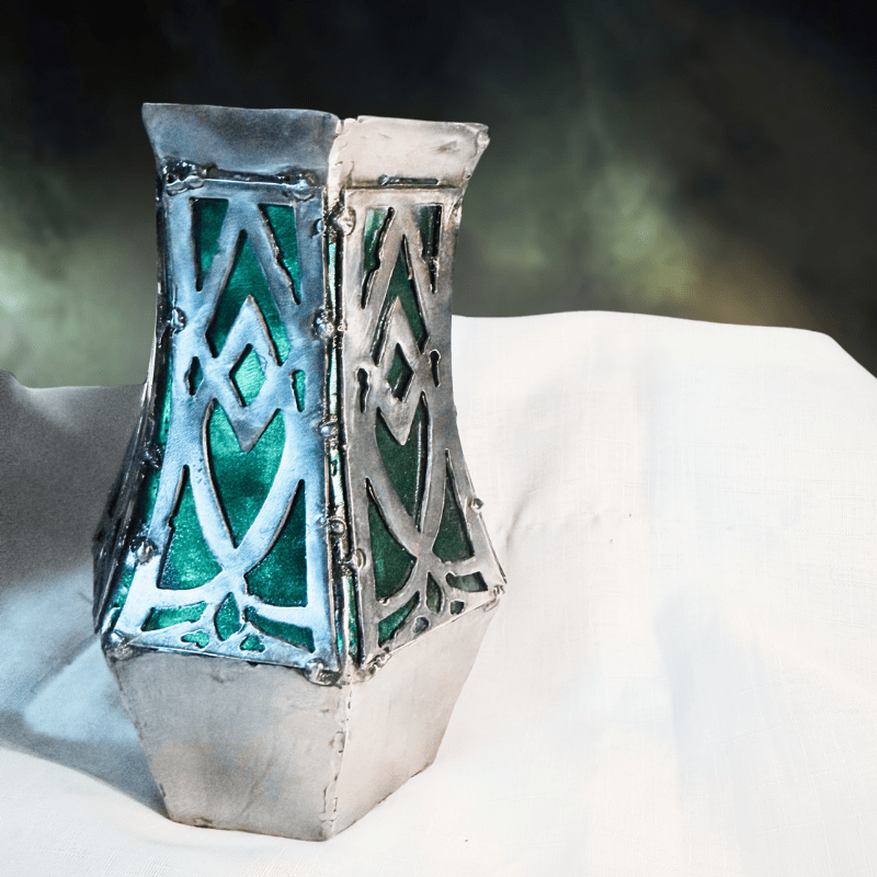 Decorative metal vase with geometric patterns on a white surface