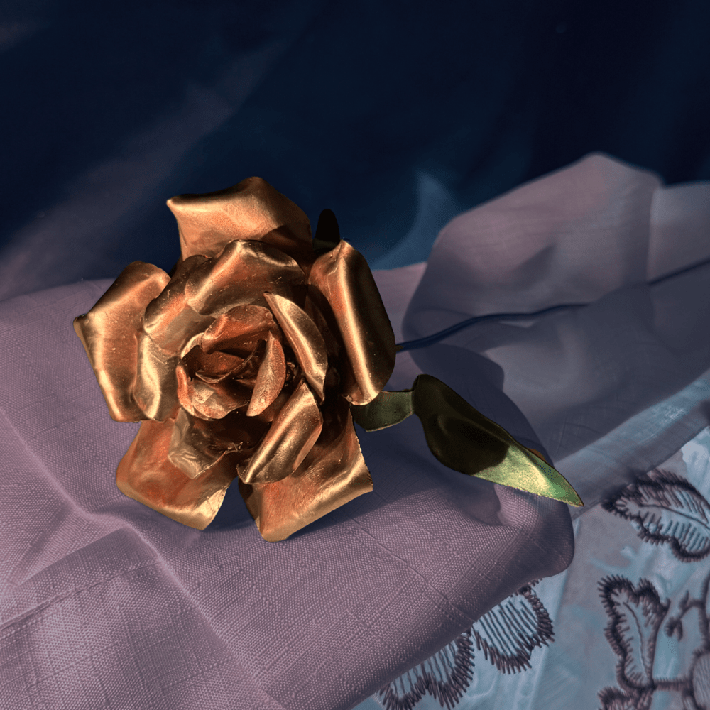 Metallic Pink Gold rose on a textured purple surface with a dark background