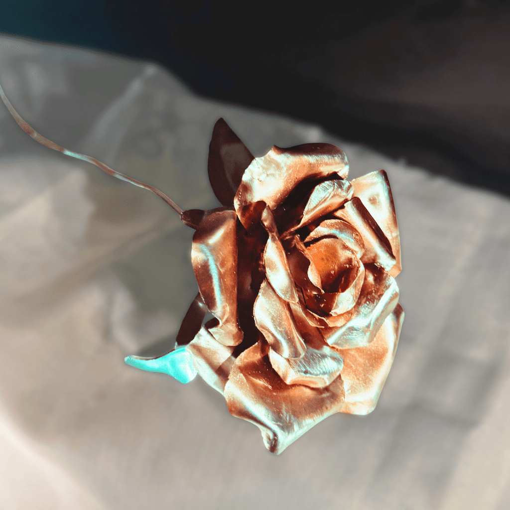 Metallic rose on a reflective surface with a dark background
