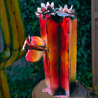 Decorative metal sculpture of a red cactus flower with a colorful gradient in a garden setting