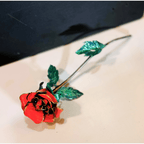 Decorative red rose with green leaves on a beige surface