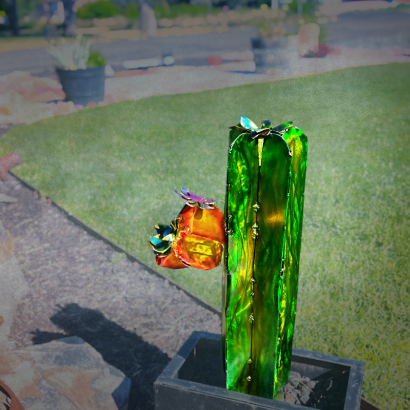 Decorative metal cactus sculpture on a patio with grass and outdoor furniture in the background.