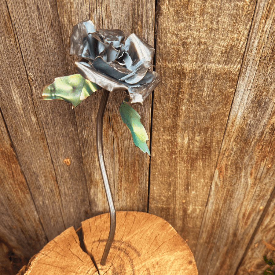 Metal flower sculpture on a wooden stump against a wooden background