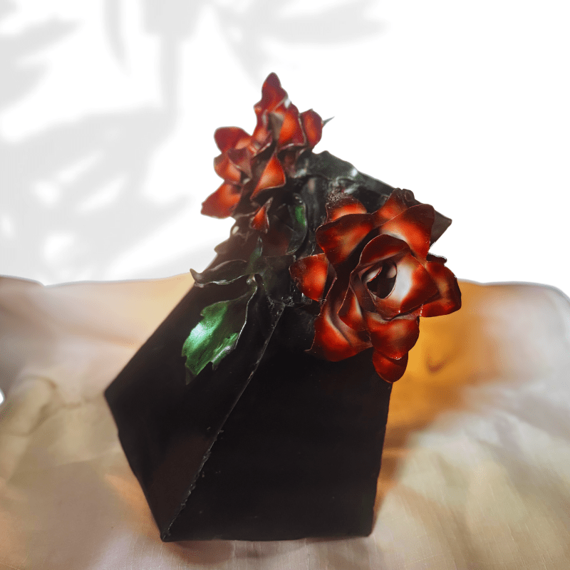 Black metal  vase with red rose design on a white background