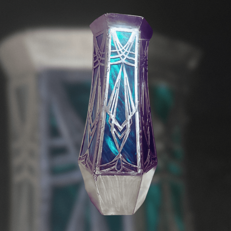 Decorative metal vase with a glass look finish and geometric design on a dark background