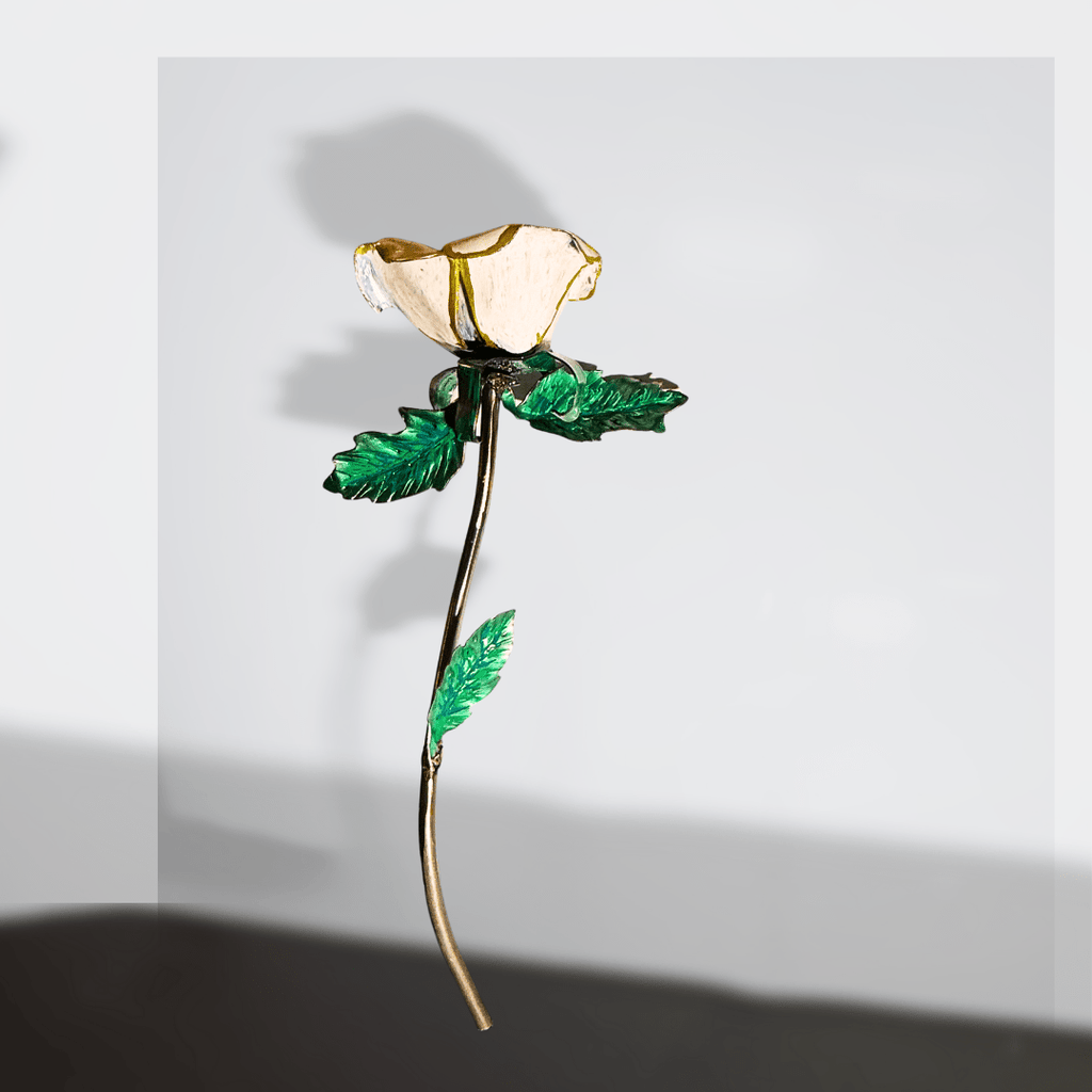 White and gold hand made metal rose with green leaves, on a gray and white blurred background