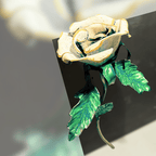Decorative rose with gold accents and green leaves on a black background