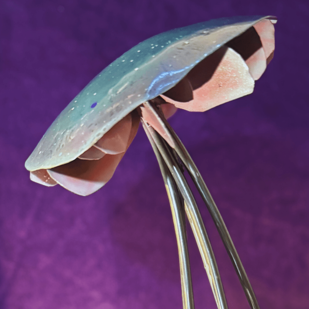 Close-up of a metallic mushroom shaped object against a purple background