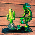 Metal sculptures of a cactus and a Kokopelli figure on a wooden surface