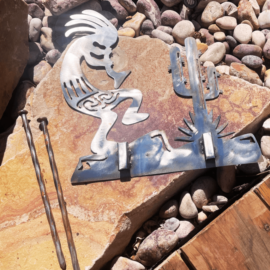 Metal sculpture of a Native American figure with a cactus on a stone surface