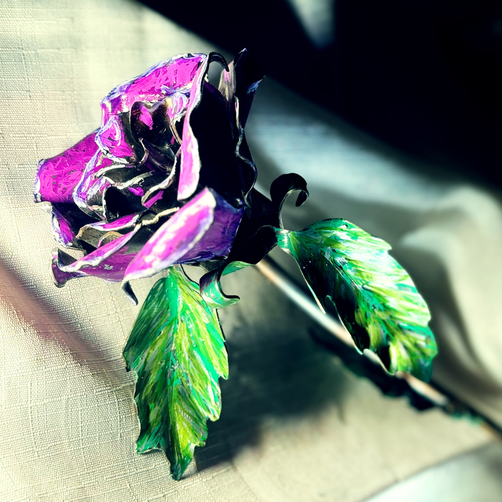 Metallic rose with purple petals and green leaves on a textured surface