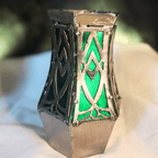 Metal vase with green and silver accents on a blurred background